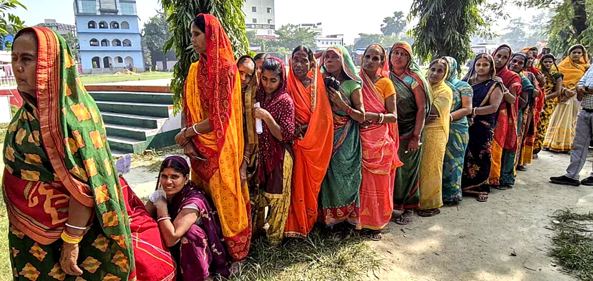 Women voters wait in a queue to cast votes at a polling station during the first phase of the Bihar Assembly elections